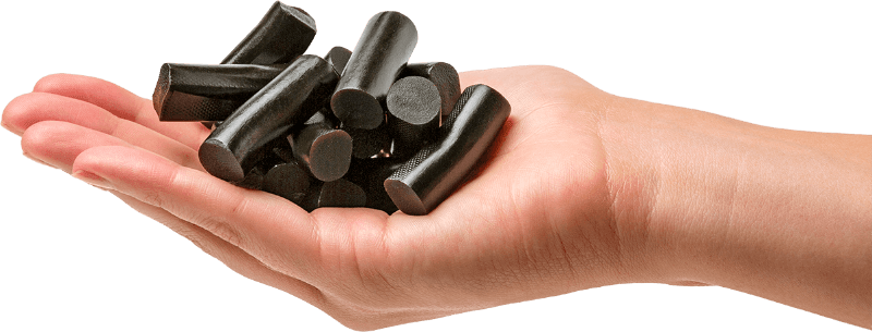 Hand holding black liquorice pieces